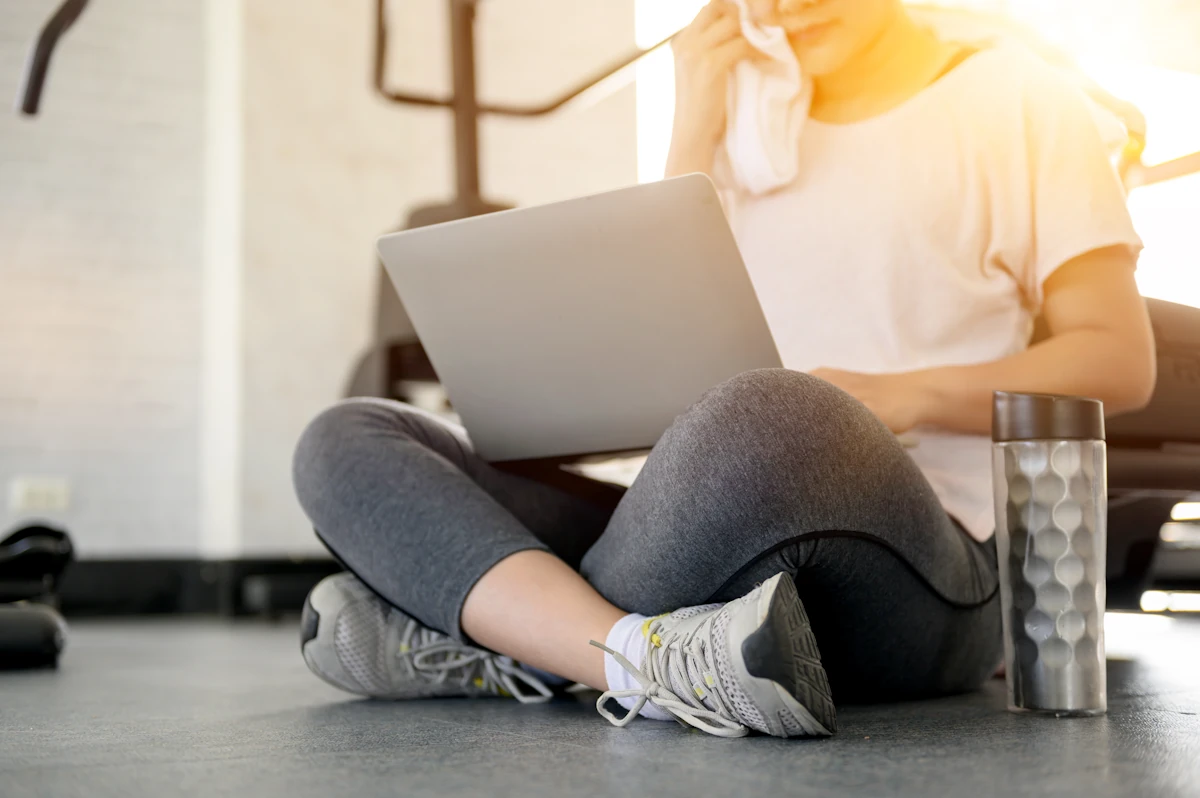 Une femme en tenue de sport qui fait une réservation en ligne salle de sport
